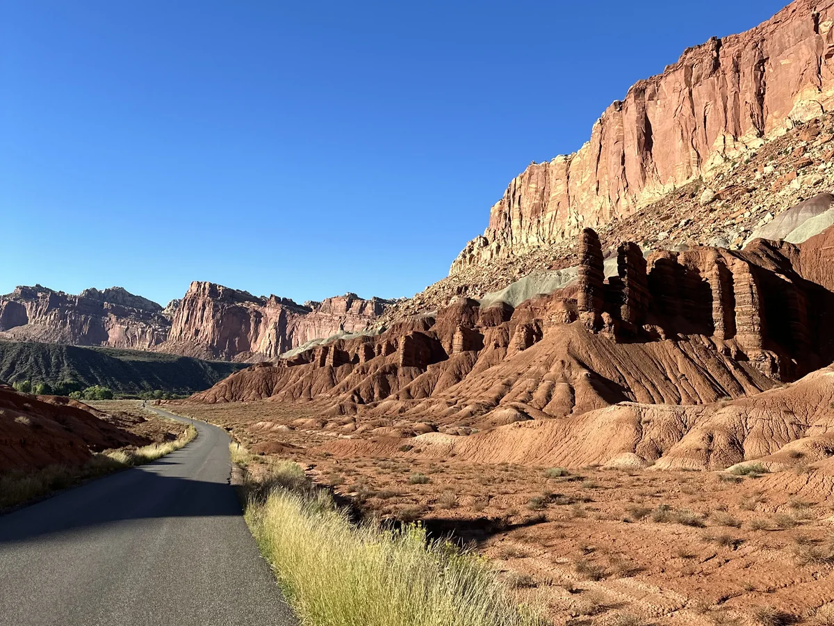 A road winding through Utah red rock formations beneath sandstone cliffs